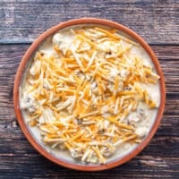 A layer of cheese is spread over the cauliflower and sauce in the casserole right before baking. The casserole is now ready to bake