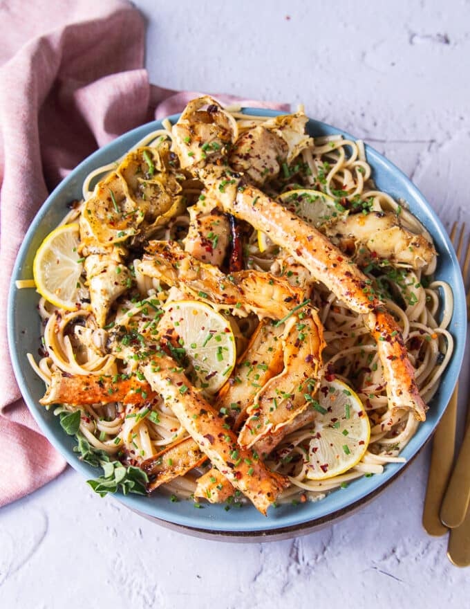 top view of a plate of crab pasta with some silverware on the side 