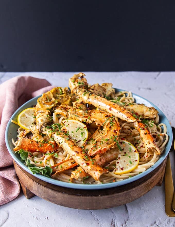 A plate of the cooked crab pasta with the crab on top and more herbs, some lemon slices and chilli flakes 