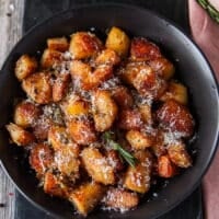 Top view close up of crispy potatoes showing the deep golden color and crisp outside of the roasted potatoes and some rosemary and parmesan on top