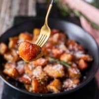 Fork holding some crispy potatoes up close showing the texture and browning