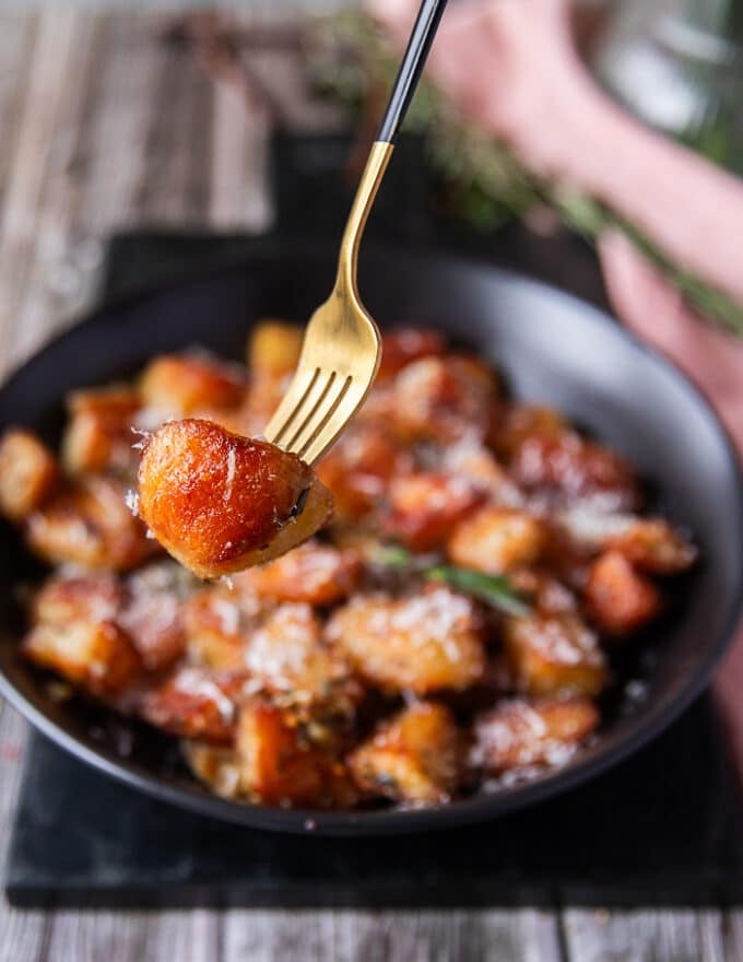 Fork holding some crispy potatoes up close showing the texture and browning