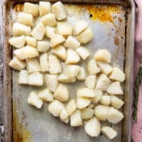 The drained potatoes added into the hot baking sheet with hot oil