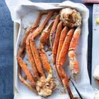 crab legs on a baking sheet seasoned with cajun spice blend and drizzled with olive oil.