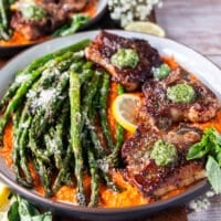 close up of the plated lamb chops showing how well cooked and buttery they are with dollops of basil pesto on top