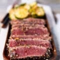 close up of a plate of seared ahi tuna stacked in slices