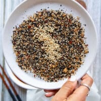 A hand holding a plate of the dried crust ingredients and mixing them together
