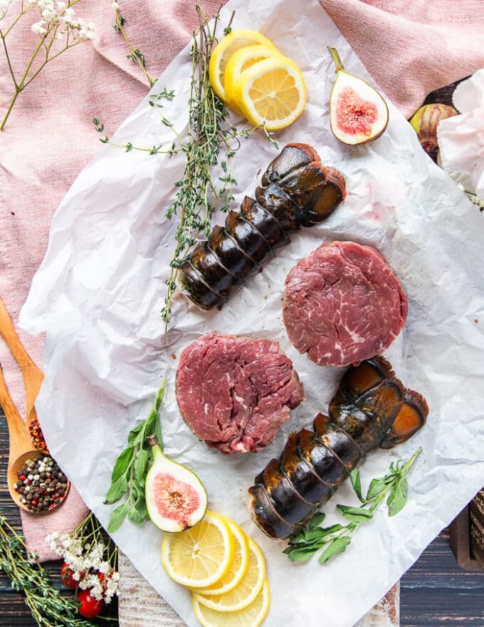 A paper with two pieces of fillet mignons and two pieces of lobster tails to make surf and turf