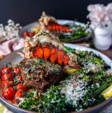A full plate of fillet mignon cooked perfectly and a lobster tail on tops with herb butter drizzling, some rapini on the side, lemon wedges and parmesan cheese for the final surf and turf plate