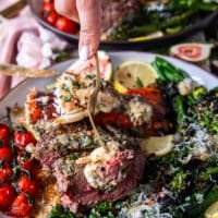 A hand holding a fork with a piece of lobster, a piece of fillet mignon and showing close up the bite