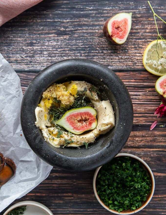 The herb butter ingredients added into a large mortar and pestle