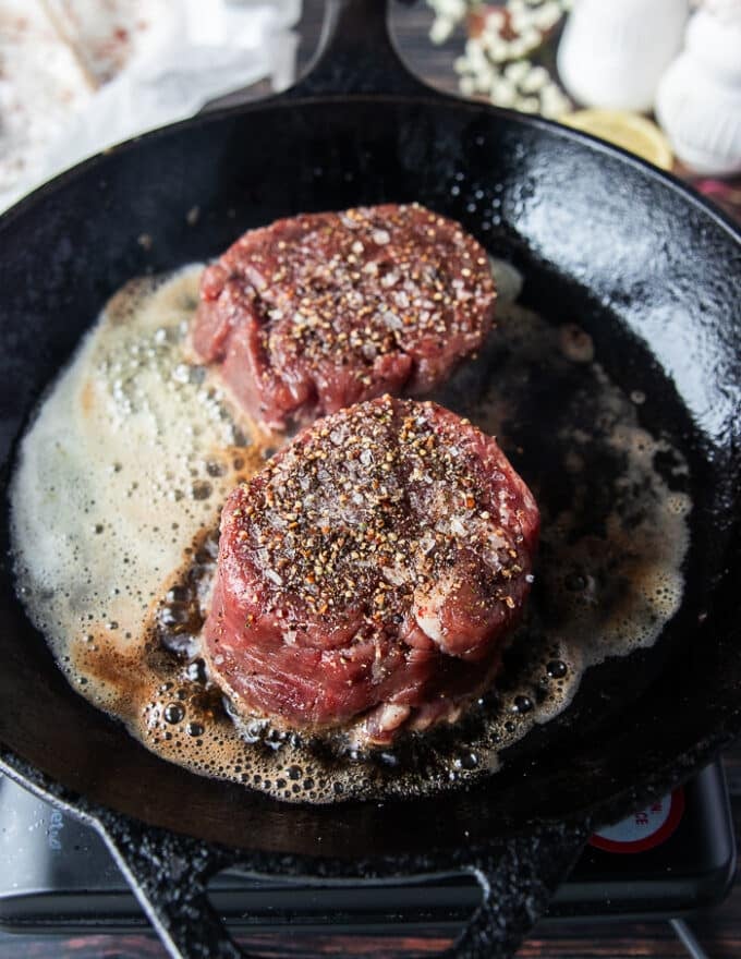 tenderloin steaks added to a cast iron skillet with butter and oil