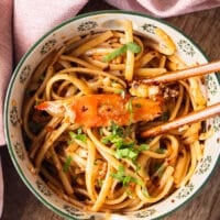 Large Crab meat added over a bowl of creamy chili crab pasta and two chopsticks on the side