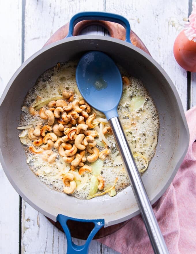 Cashews are added to the rice pan with onion and butter when the onions have softened 