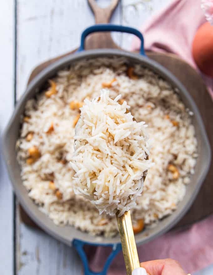 A spoon showing close up of the cooked fluffy coconut rice 