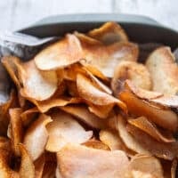 close up of crispy fried potato chips showing the crispiness and seasoning and golden color