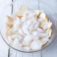 Thinly sliced potatoes in an ice bowl soaking for potato chips