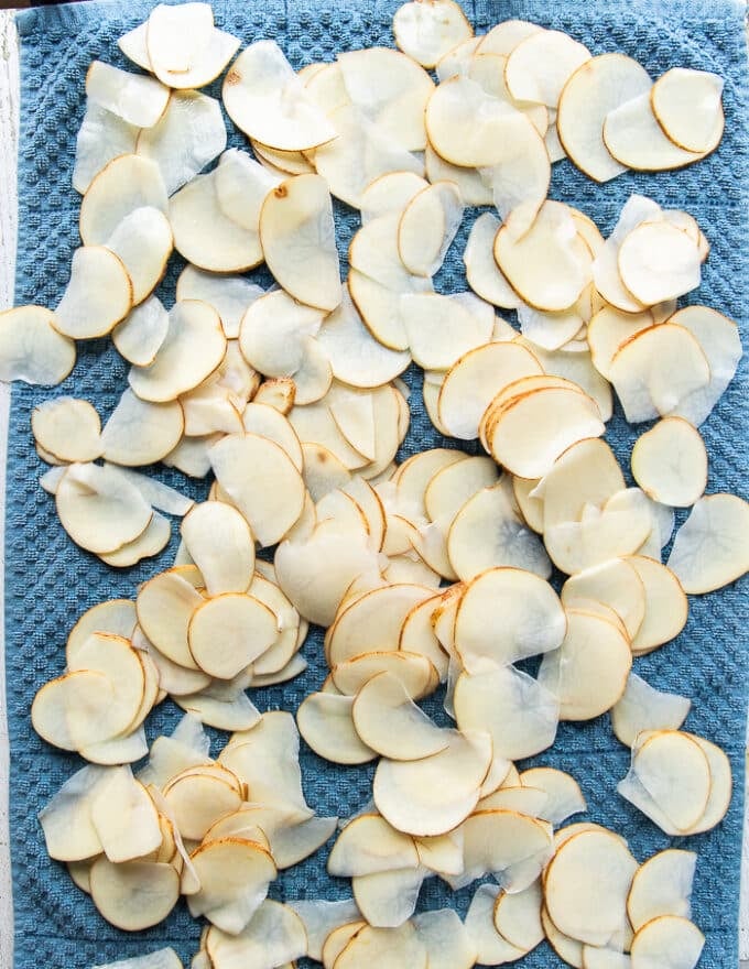 The potato slices spread in a single layer over a kitchen towel to dry 