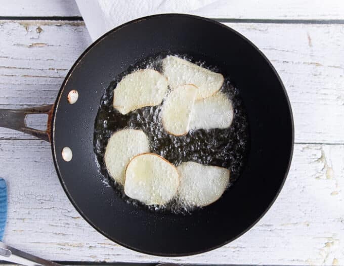 a few potato slices frying in very hot oil 