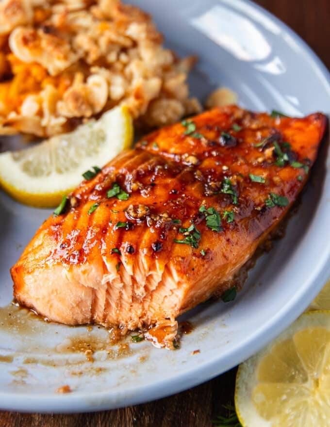maple glazed salmon on a plate, flakes with a fork showing how juicy the salmon is