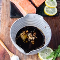 maple glaze ingredients all added into a large bowl and a hand holding a whisk to blend it