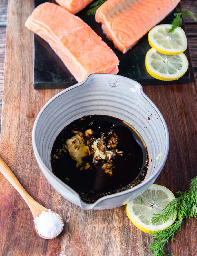 maple glaze ingredients all added into a large bowl and a hand holding a whisk to blend it