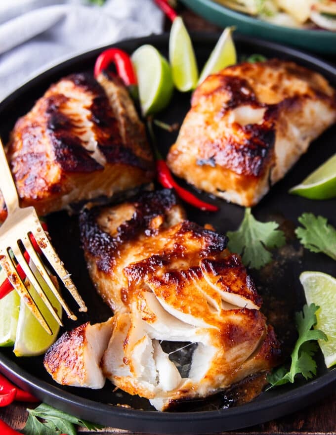 A fork flaking the miso cod showing how buttery the black cod is