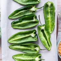 Poblano peppers cut in half and laid. on a baking sheet with cut up side facing up