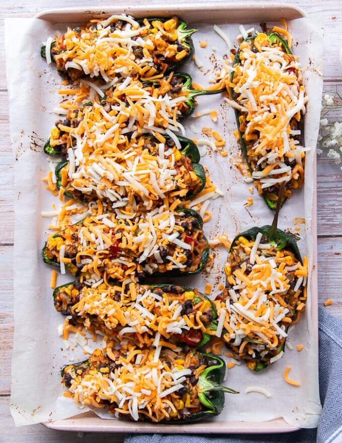 Cheese is sprinkled over the stuffed poblanos as a final step before baking for another 5 minutes to melt the cheese 
