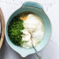 A bowl with all the dressing ingredients added in and a spoon used to mix it up