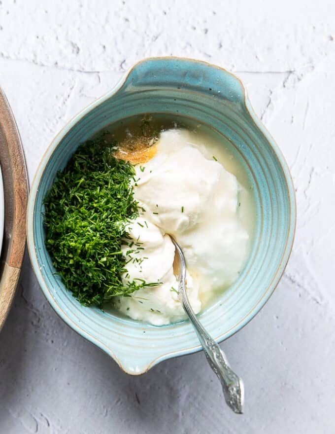 A bowl with all the dressing ingredients added in and a spoon used to mix it up