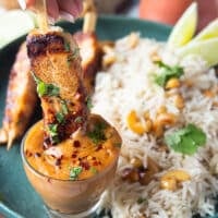 The grilled halibut skewer dipped in a bowl of satay sauce
