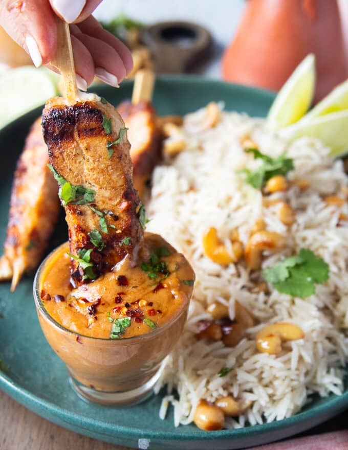 The grilled halibut skewer dipped in a bowl of satay sauce
