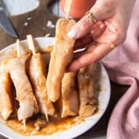 A hand holding the skewered piece of fish showing how well it keeps the shape