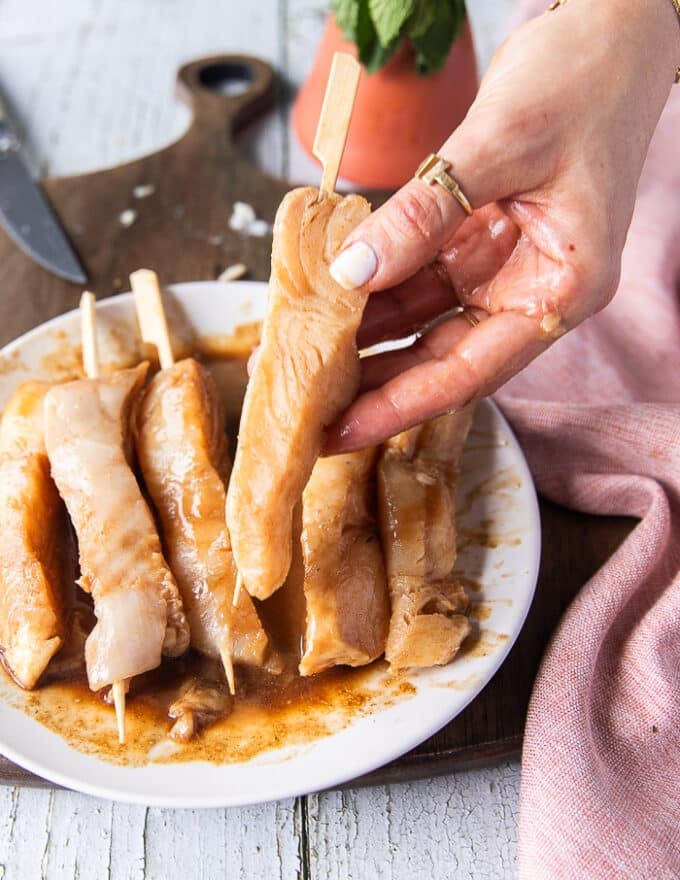 A hand holding the skewered piece of fish showing how well it keeps the shape 
