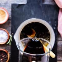 a hand pouring some balsamic vinegar in to a pot to make balsamic glaze