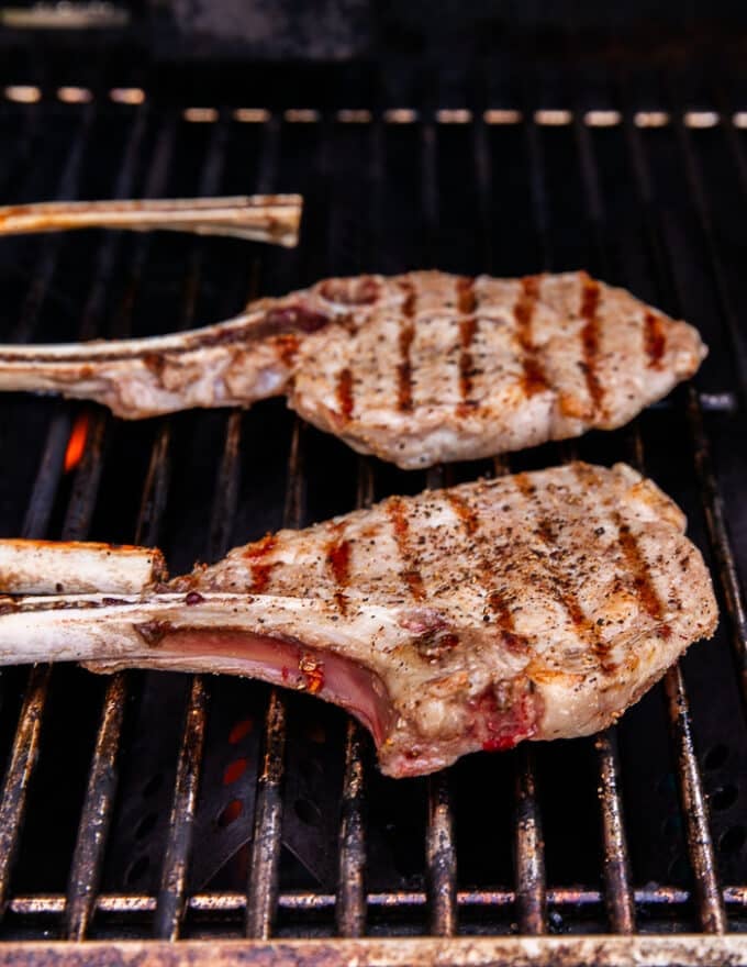 two veal chops on a grill flipped over showing the grill marks 