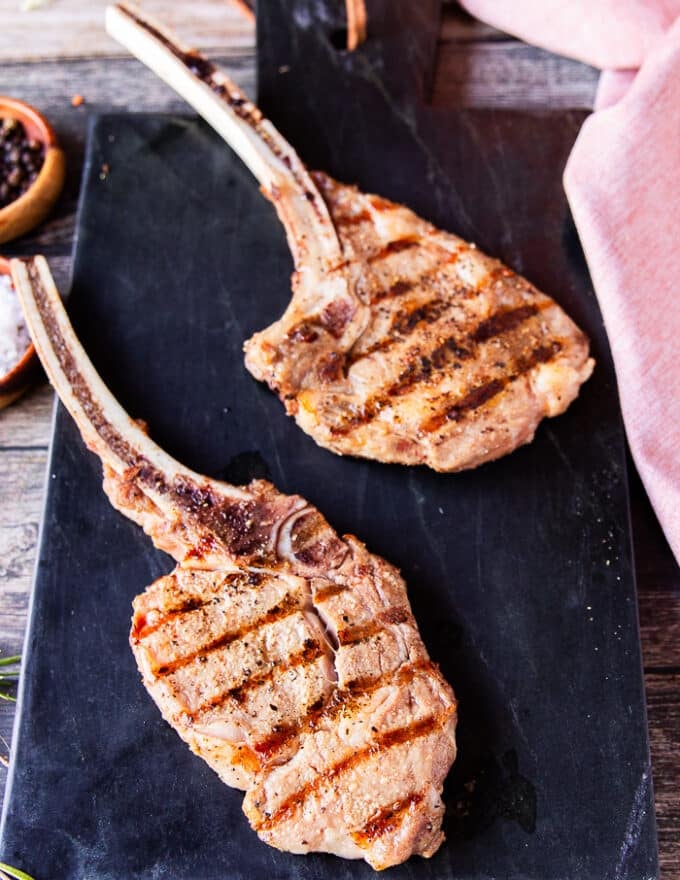 two perfectly grilled veal chops with grill marks resting on a marble after grilling 