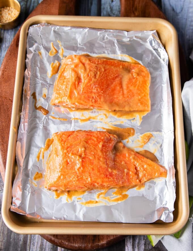 The salmon fillet drenched in miso marinade on both sides on a baking sheet