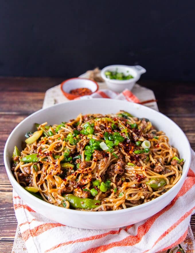 side view of the Mongolian Ground Beef Noodles cooked and served on a bowl with plenty of green onions and chilli flakes on top
