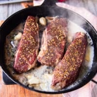 The oven cooked steaks are placed in a heavy duty cast iron pan with lots of butter for achieving the seared crust