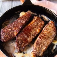 flipped steak basted with butter in a cast iron skillet with a beautiful golden crust