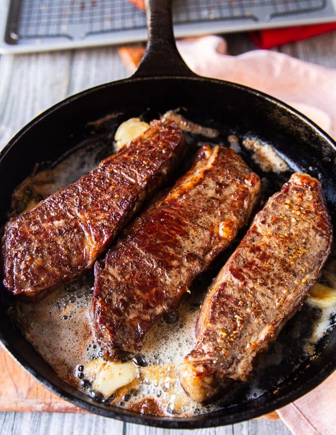 flipped steak basted with butter in a cast iron skillet with a beautiful golden crust