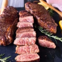 A sliced reverse sear steak on a black marble showing the perfect medium rare cooked inside of the steaks