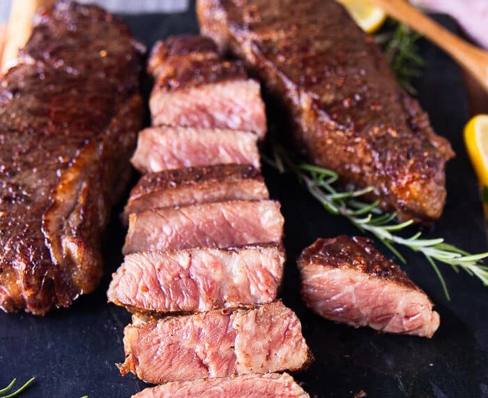 A sliced reverse sear steak on a black marble showing the perfect medium rare cooked inside of the steaks
