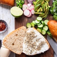A rustic sandwich bread cut in half and spread with cream cheese, and sprinkled with bagel seasoning