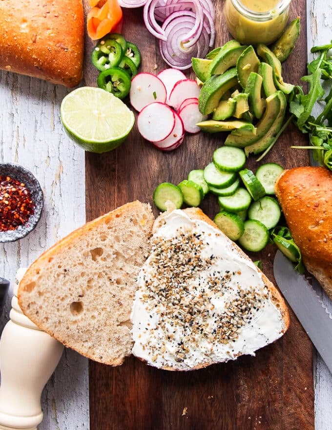 A rustic sandwich bread cut in half and spread with cream cheese, and sprinkled with bagel seasoning 