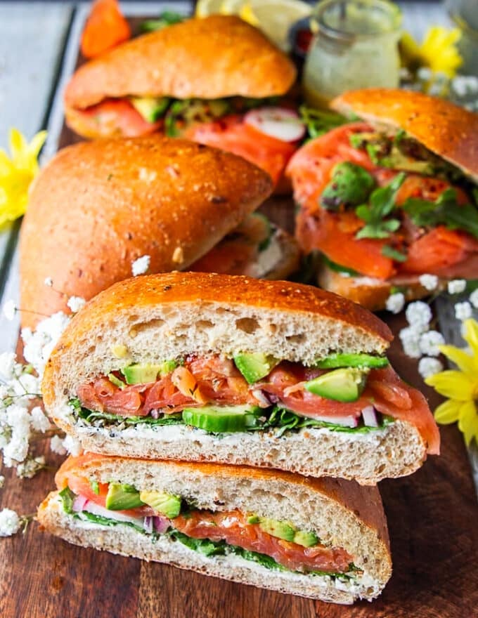 one sliced smoked salmon sandwich on a board surrounded by other sandwiches 