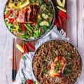 two plates of soba noodles, one served warm and the other cold with veggies