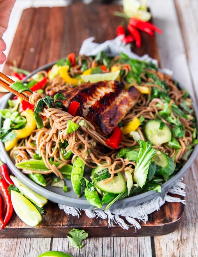 A hand holding two chopsticks showing how to stretch the noodles with the soba noodle salad